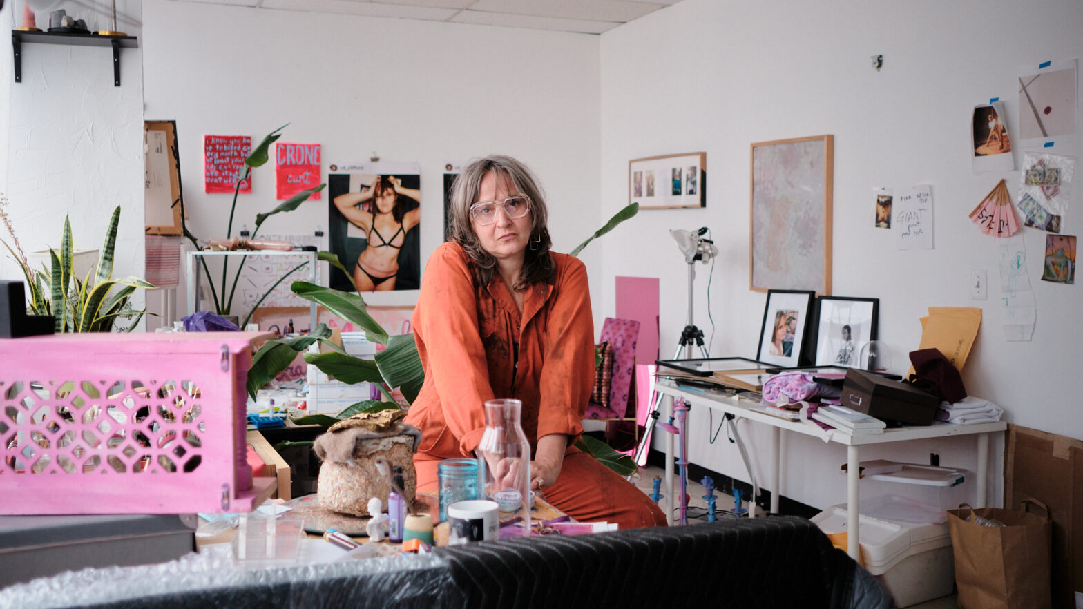 A woman sitting on a stool in an art studio.