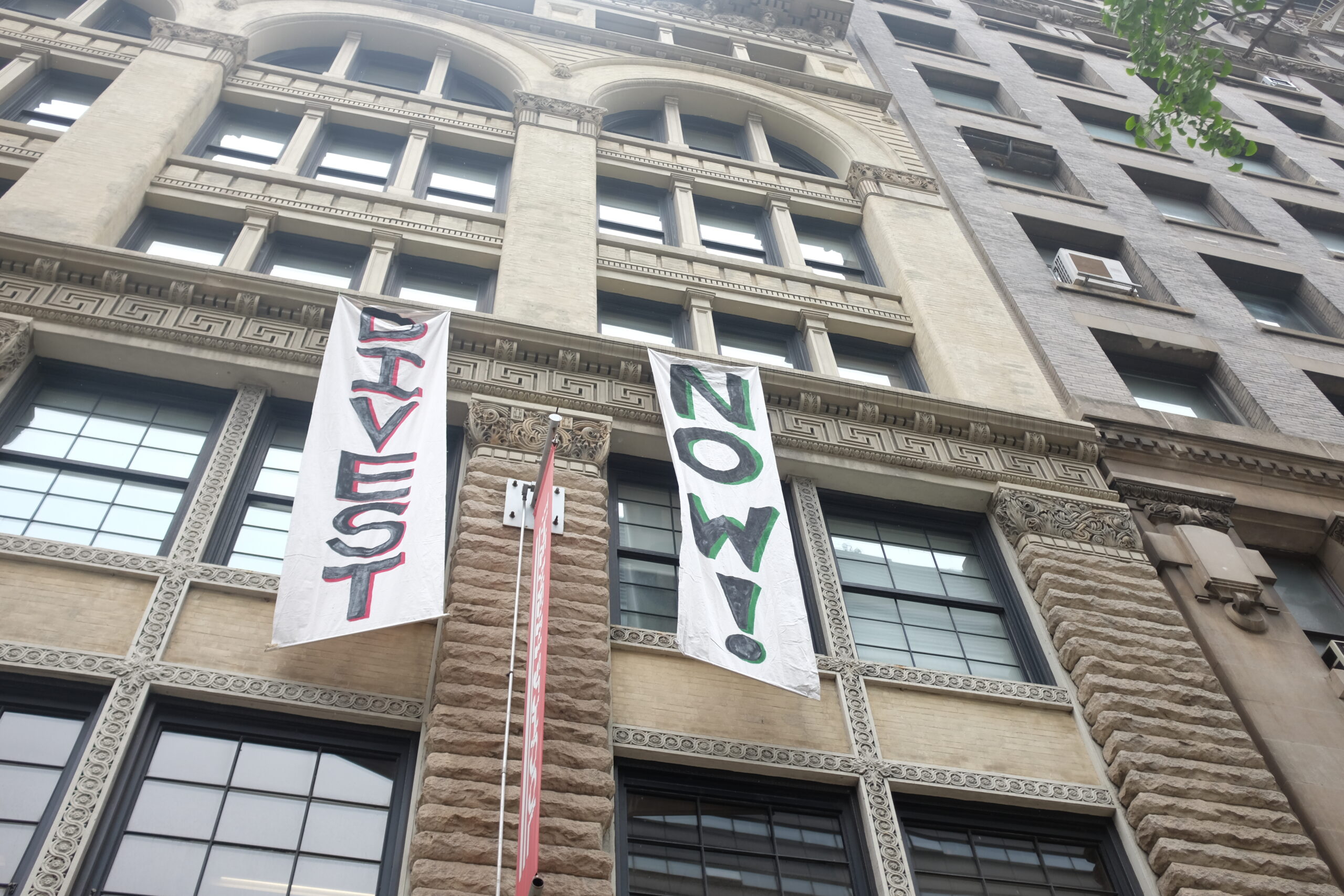 Banners that say, “Divest now” in front of the The New School Welcome Center