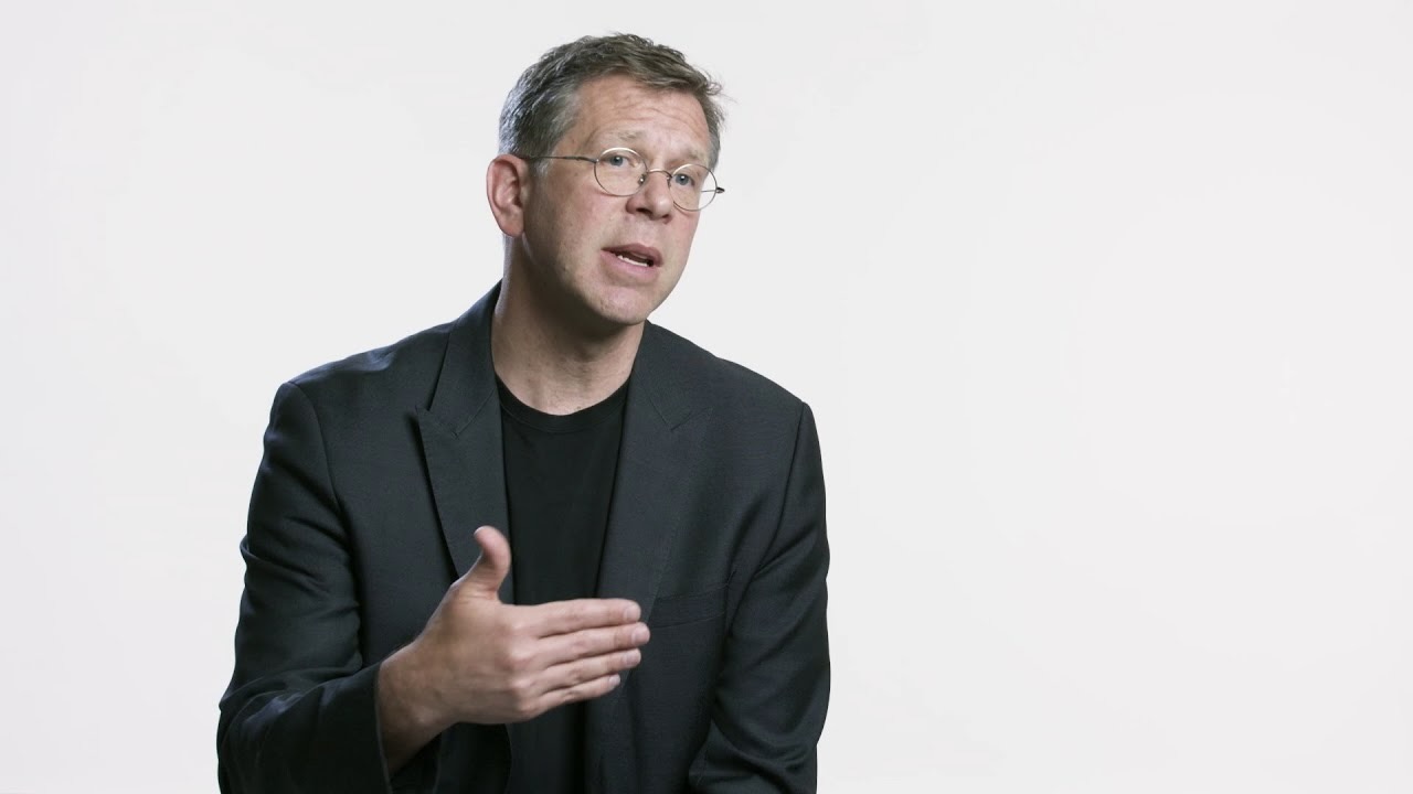 President Joel Towers dressed in a black suit in front of a white backdrop.