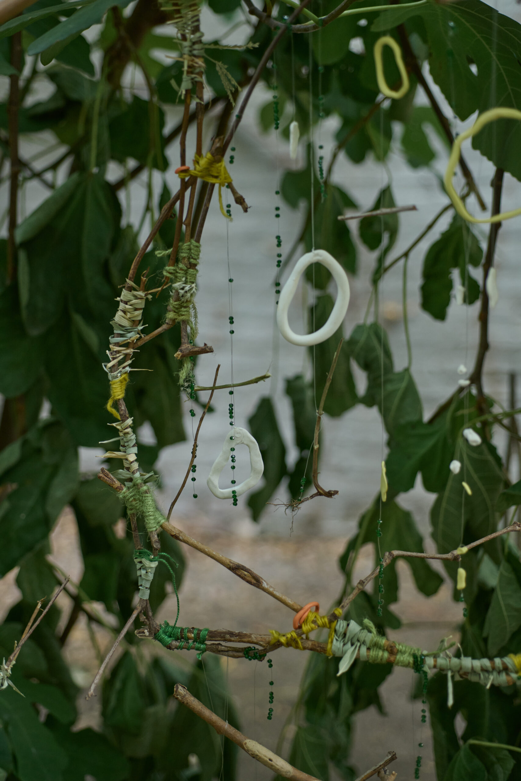 Small pieces of "found material" from the garden held together by string and yarn hung on a tree.