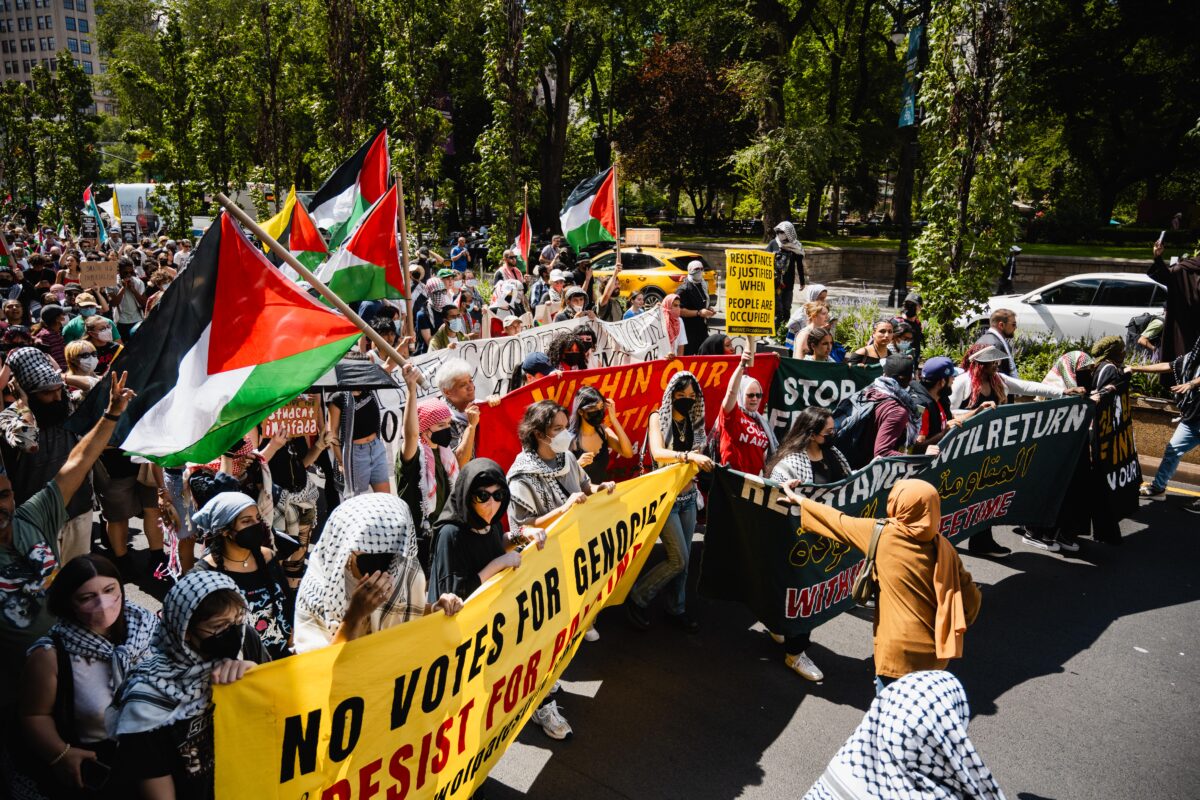 crowd of protesters marching and holding palestinian flags