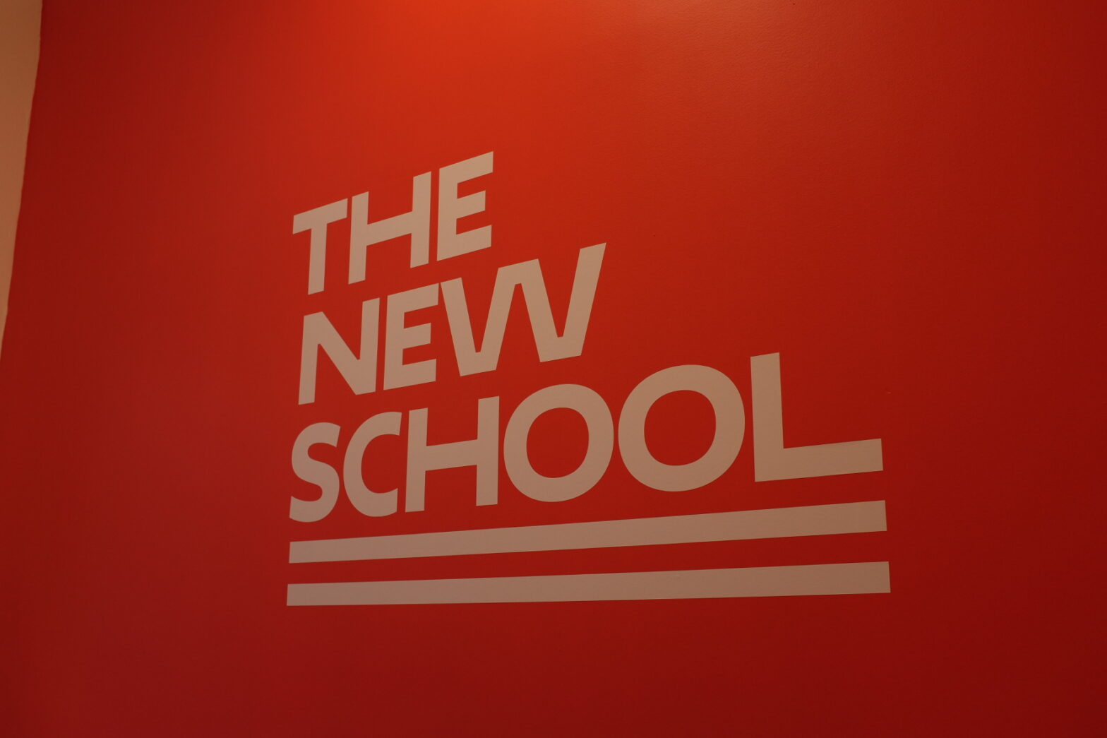 The New School logo printed in white on a red wall.