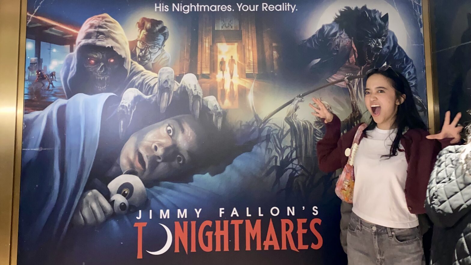 Student stands in front of Jimmy Fallon’s haunted maze poster titled Tonightmares.