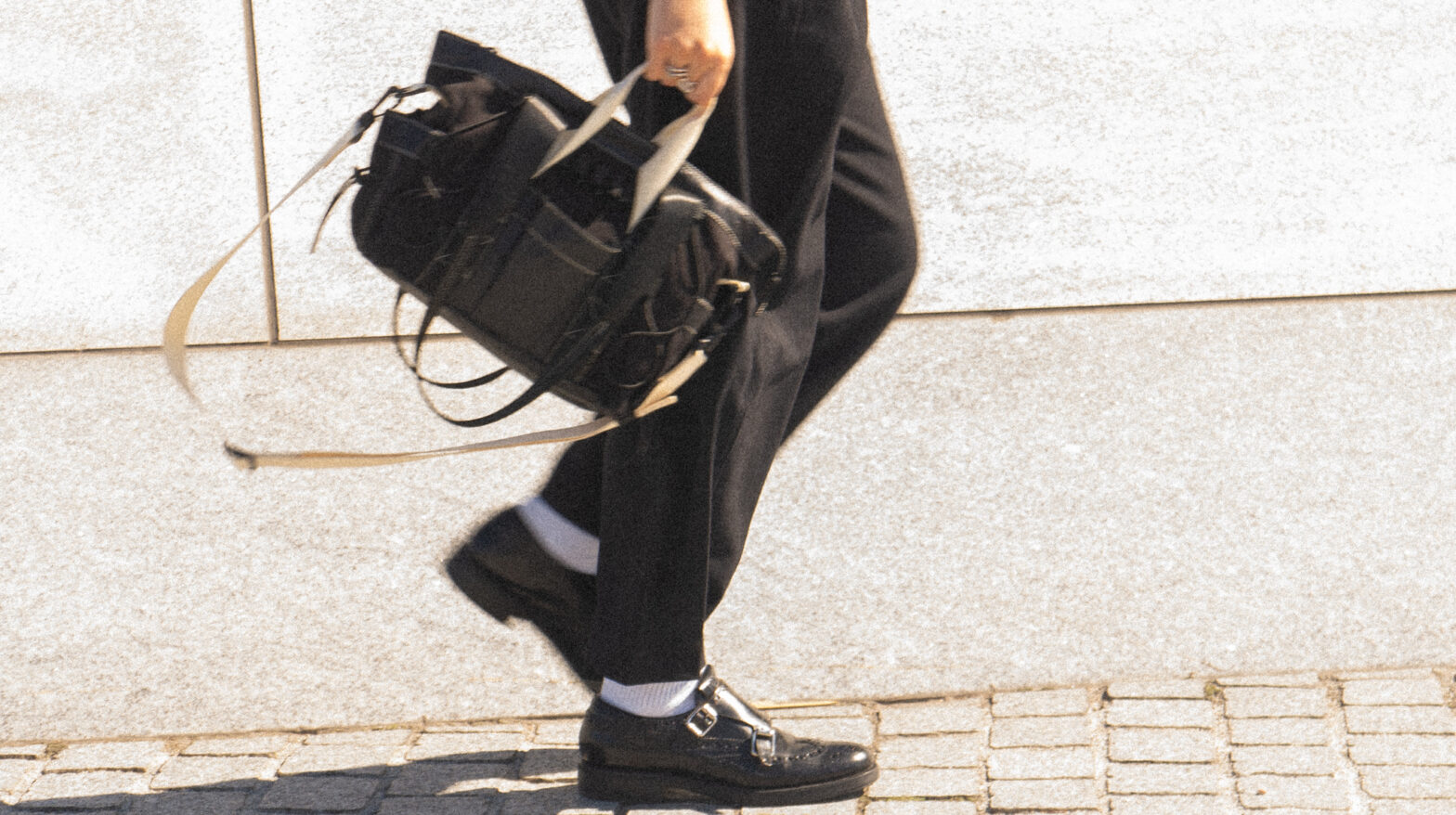 Blurry shot of the FHD Utility Tote being carried while walking against a stone background.