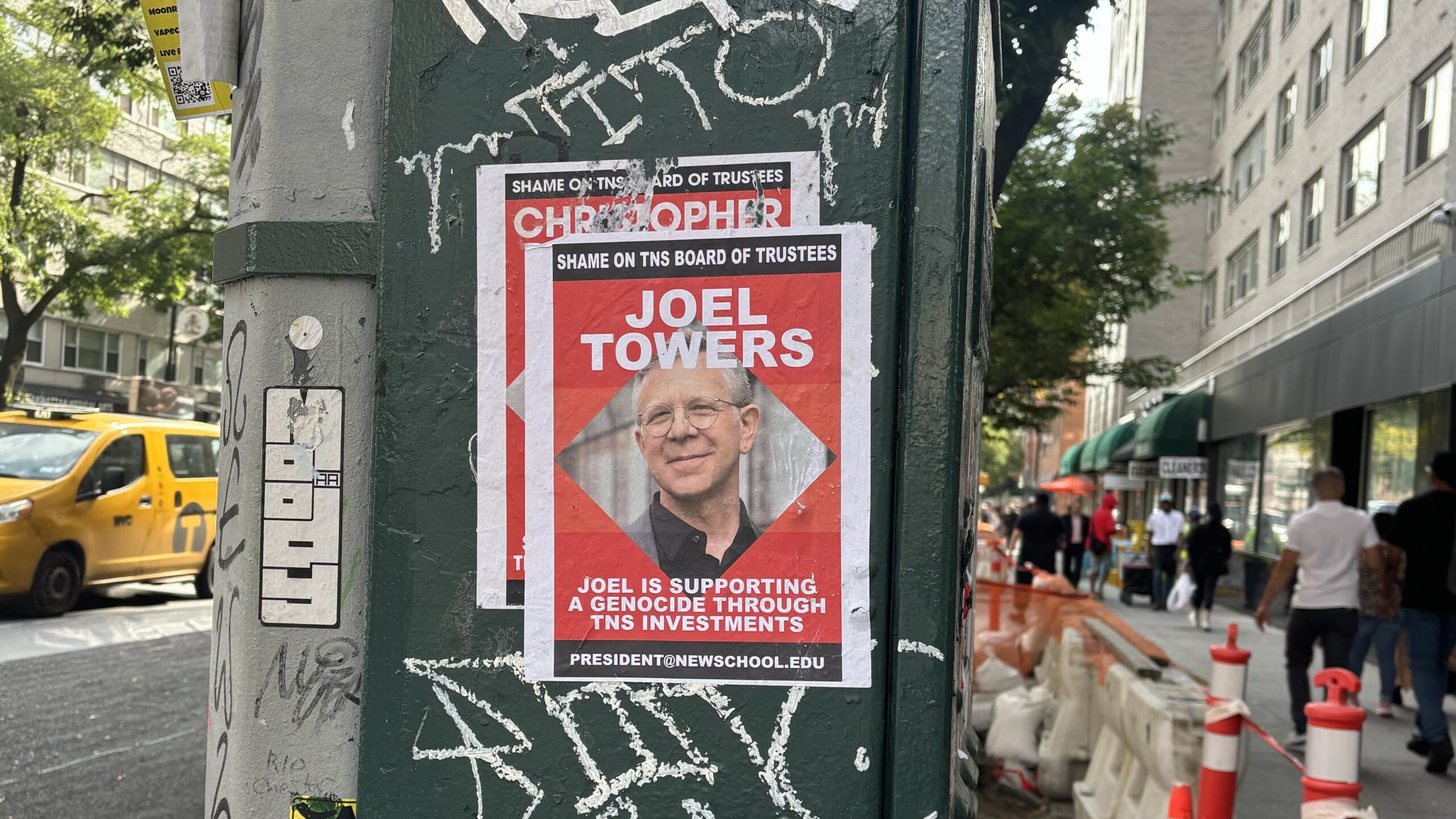 A sign on a street post with a photo of Joel Towers with text “JOEL TOWERS” “JOEL IS SUPPORTING GENOCIDE THROUGH TNS INVESTMENTS"