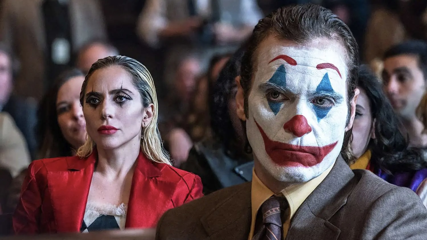 man and woman sitting in a courtroom with their faces painted like clowns.