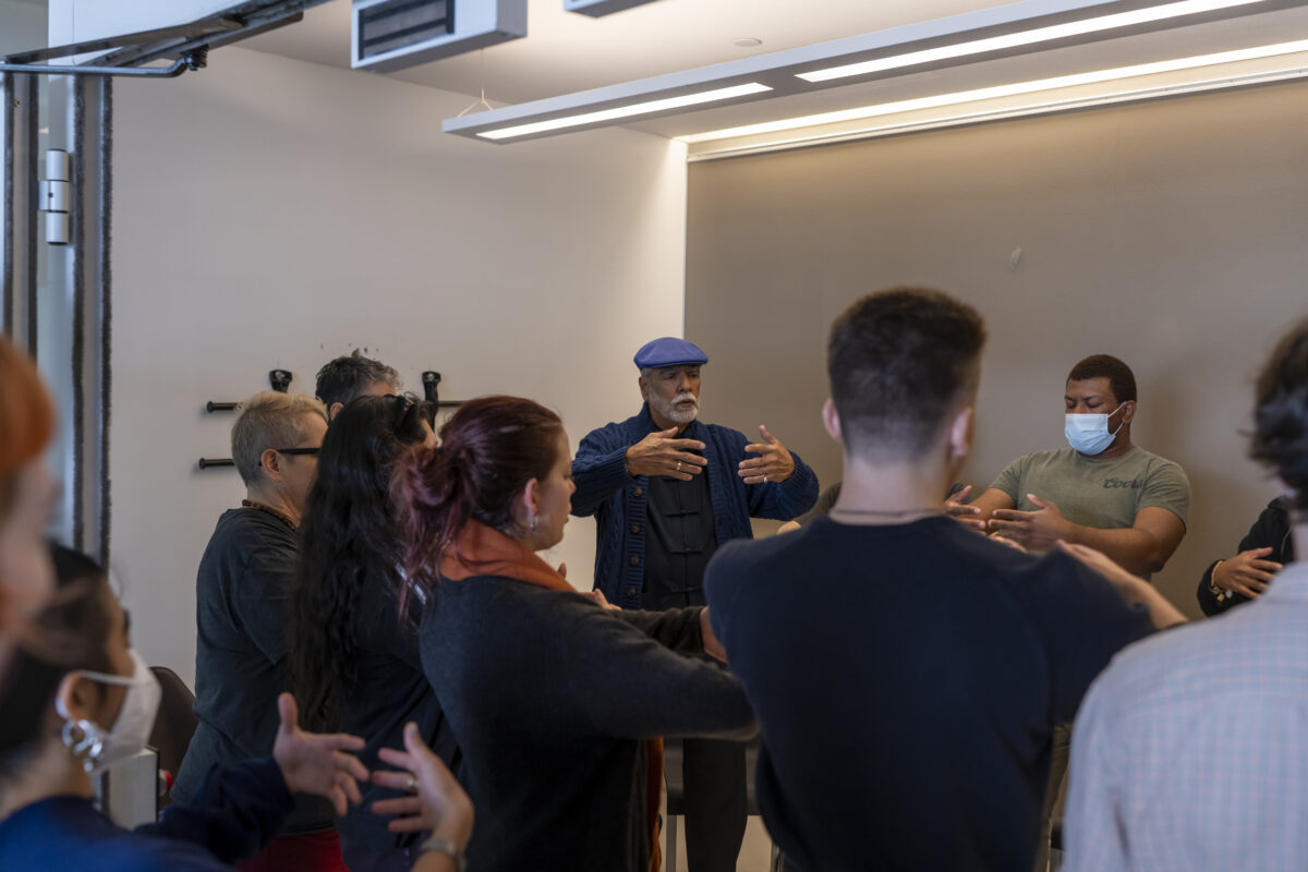 People in group standing and hugging air with their eyes closed in meditation