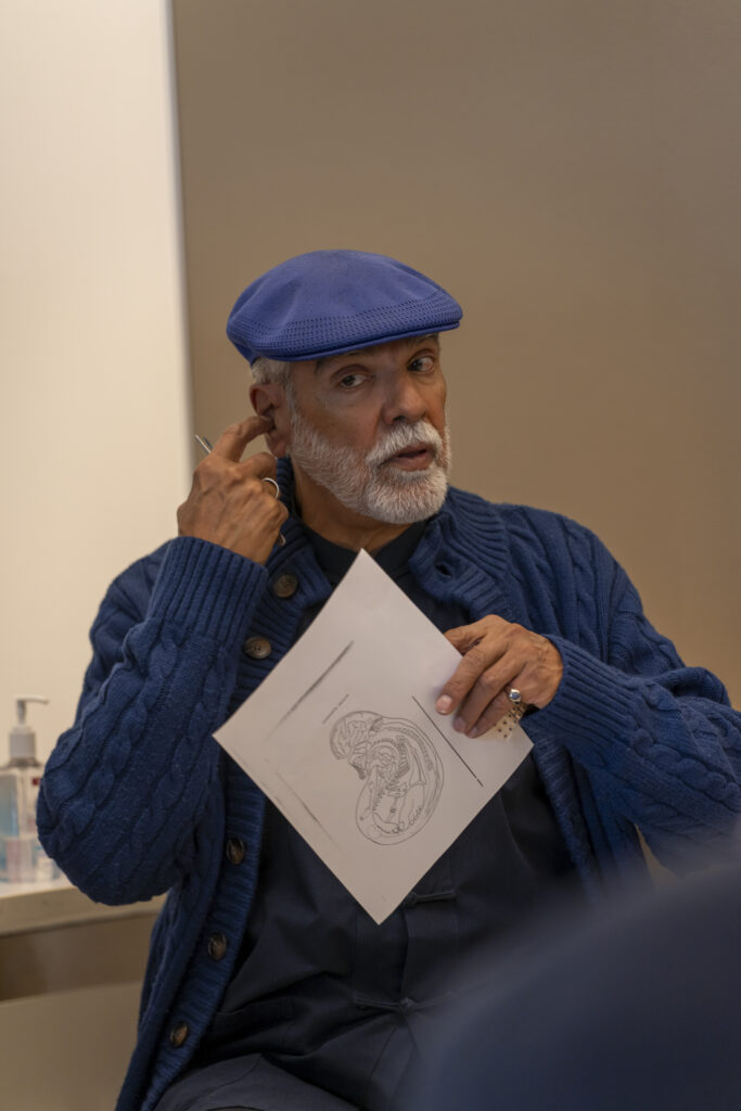 Man in a blue sweater and a blue hat pointing towards inner ear while explaining anatomy