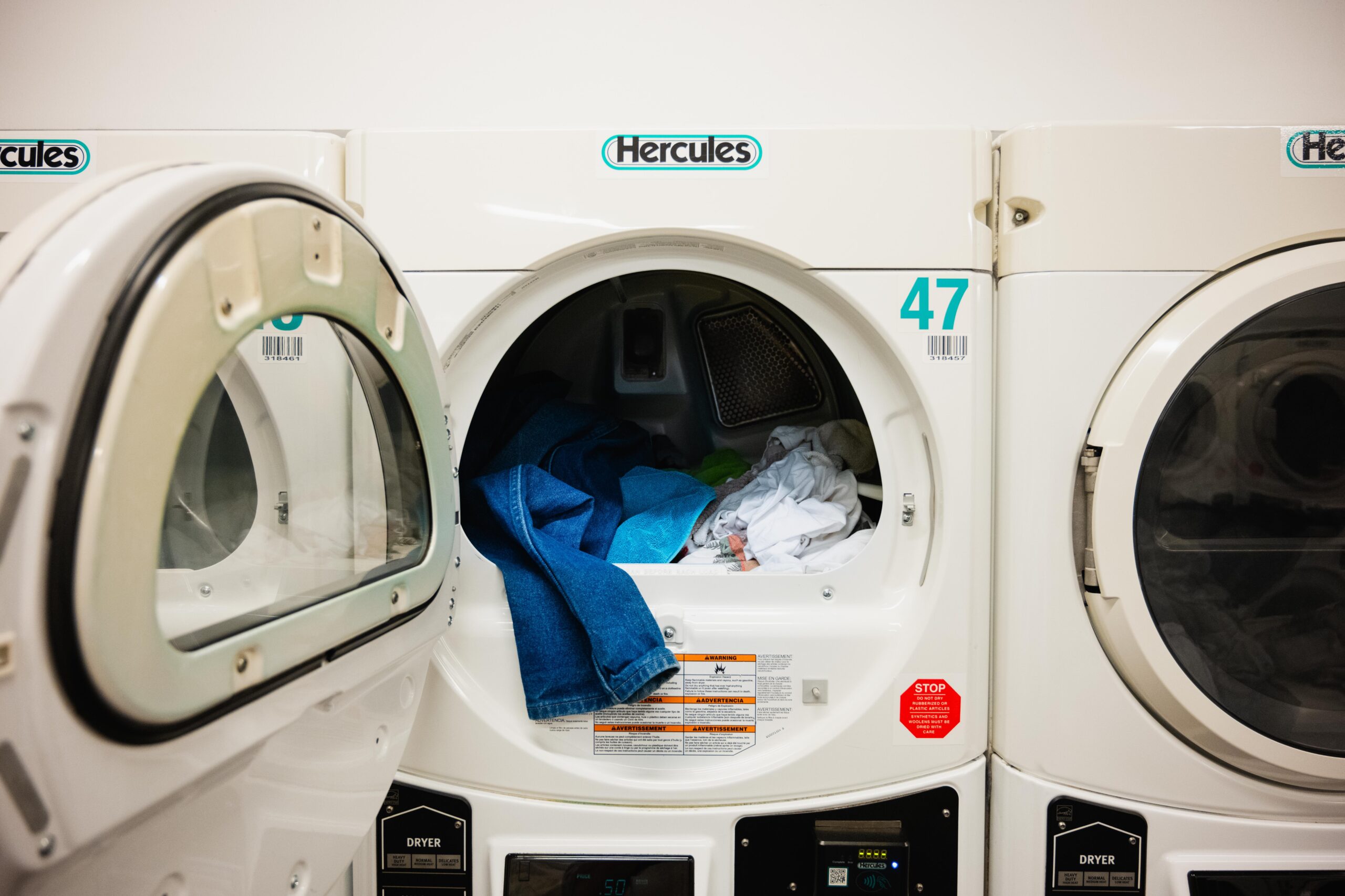 A Hercules washing machine with the door open, with laundry inside.