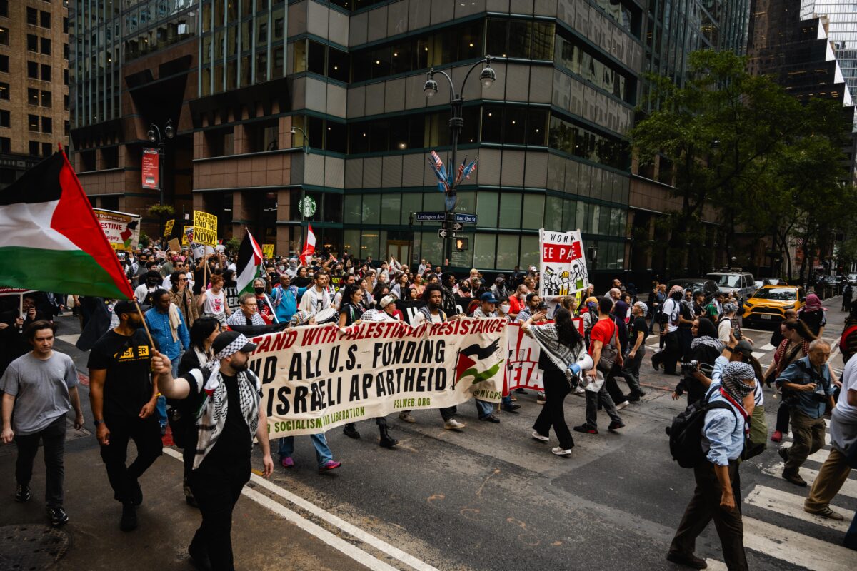 Demonstrators walking down Lexington Ave holding up signs and waving the Palestine flag.