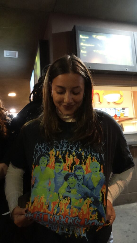 A girl pulling her shirt  with a green, blue, and neon orange design down for the camera