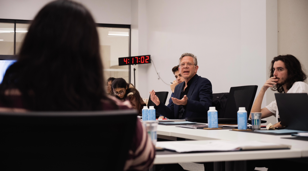 Joel Towers sitting at the long white senate table with other senators, in mid-discussion.