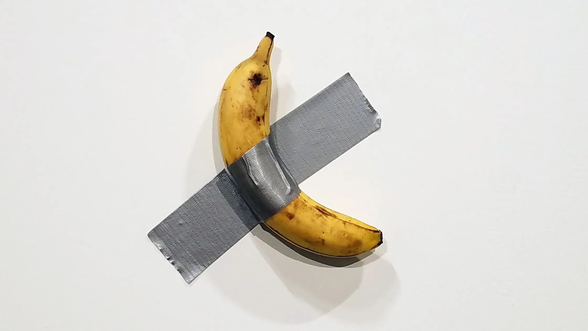 A banana duct taped on the wall.