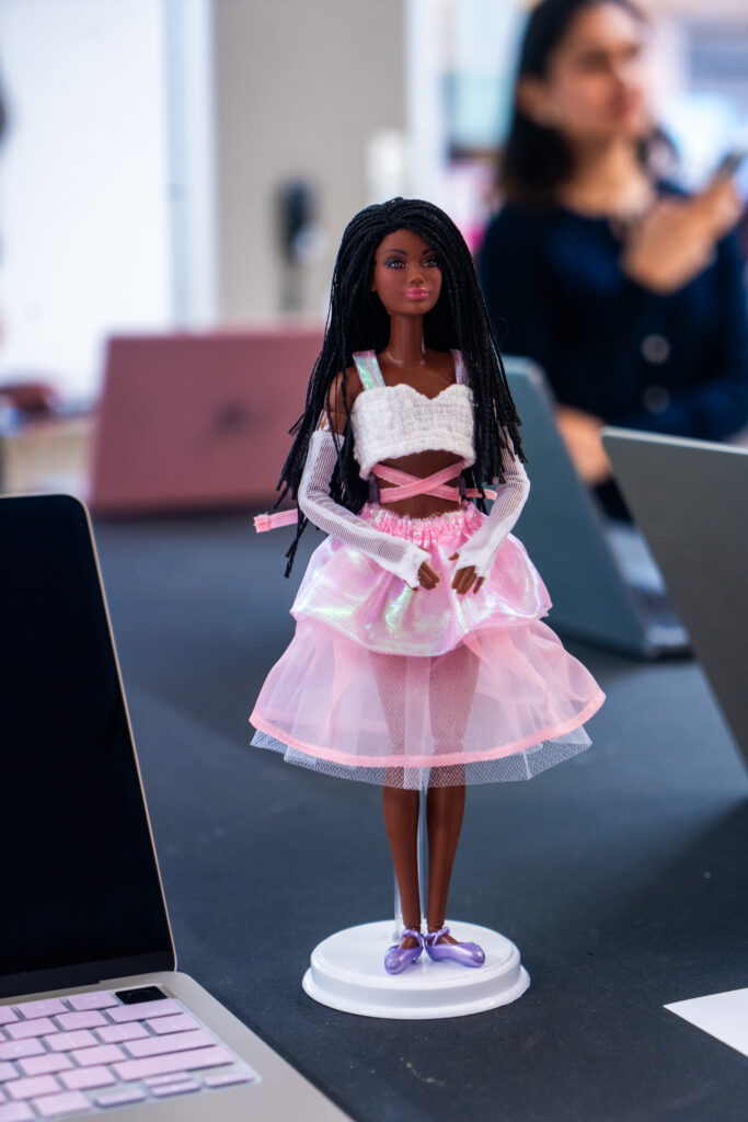 A barbie doll with dark braided hair dressed in a pink and white outfit. 