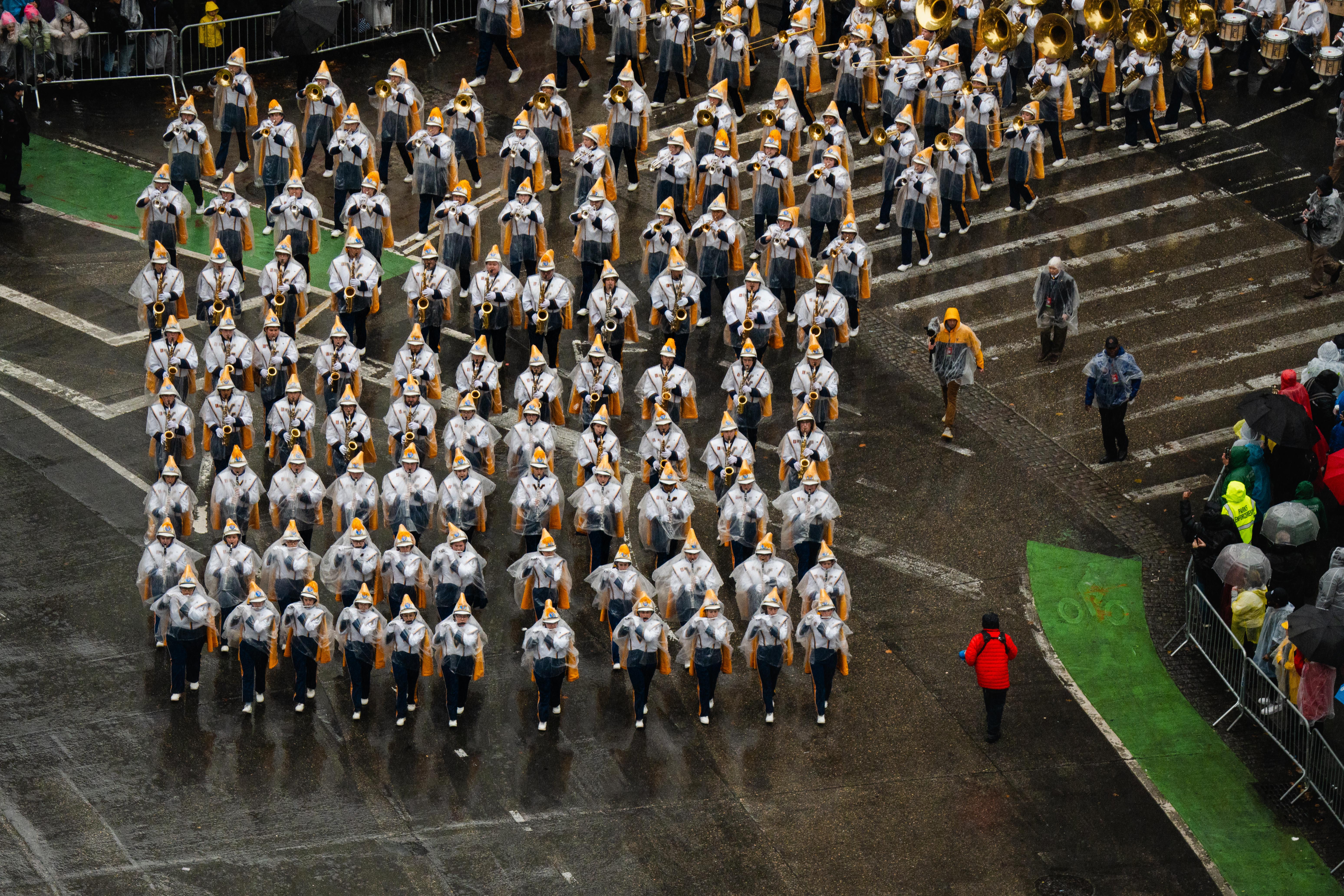 A top view of a marching band in yellow and white makes its way around Columbus Circle. 