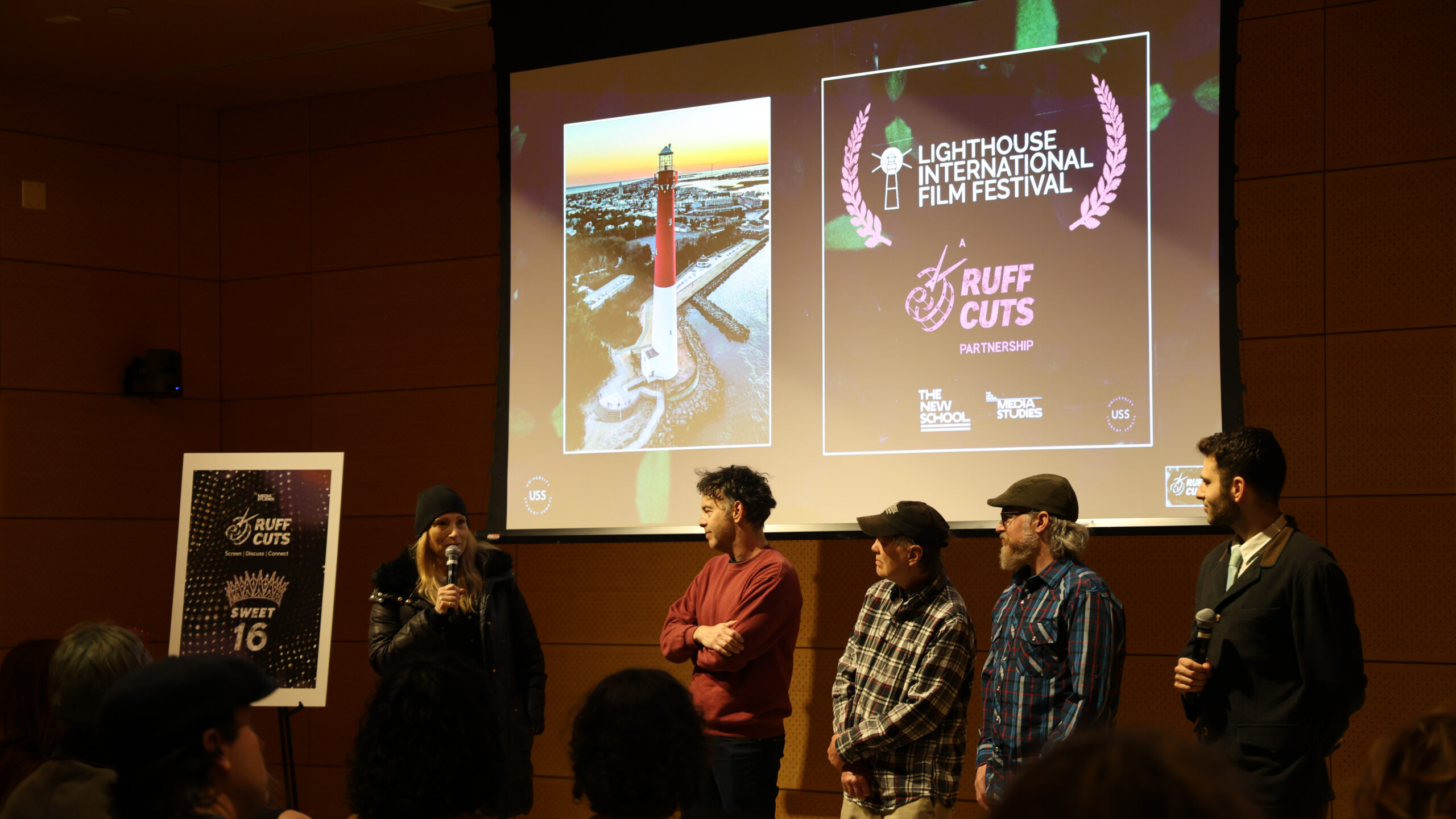 Five people standing in front of a projector screen with an image of a lighthouse and text that reads Lighthouse International Film Festival and Ruff Cuts.