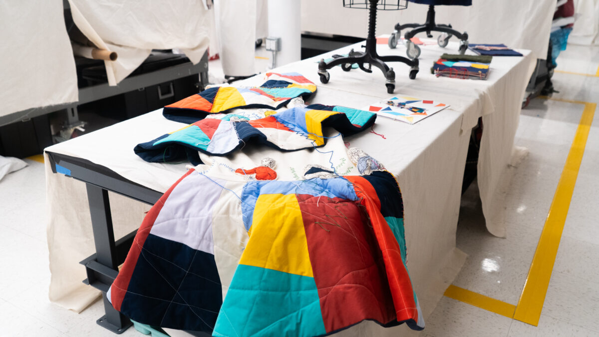 Multicolored fabric with thread is displayed on white table.