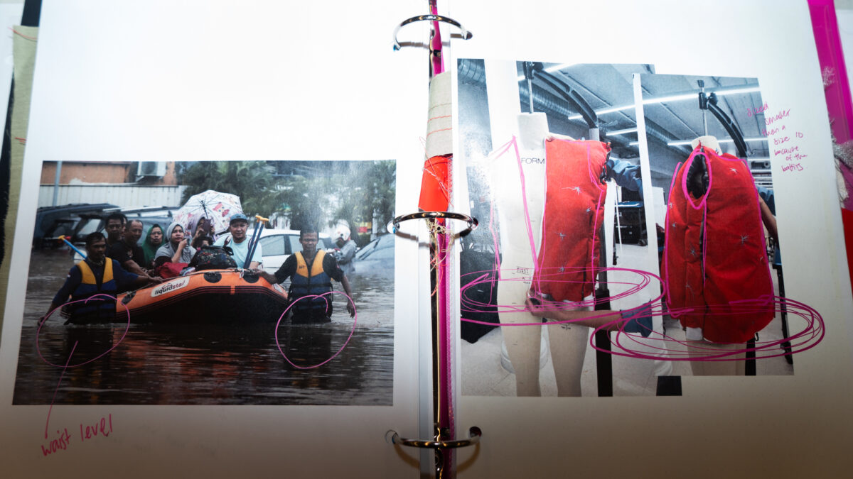 Process book spread features a photo of people being rescued in a flood on the left and images of a red life vest prototype on mannequins on the right. Annotated with pink markings.