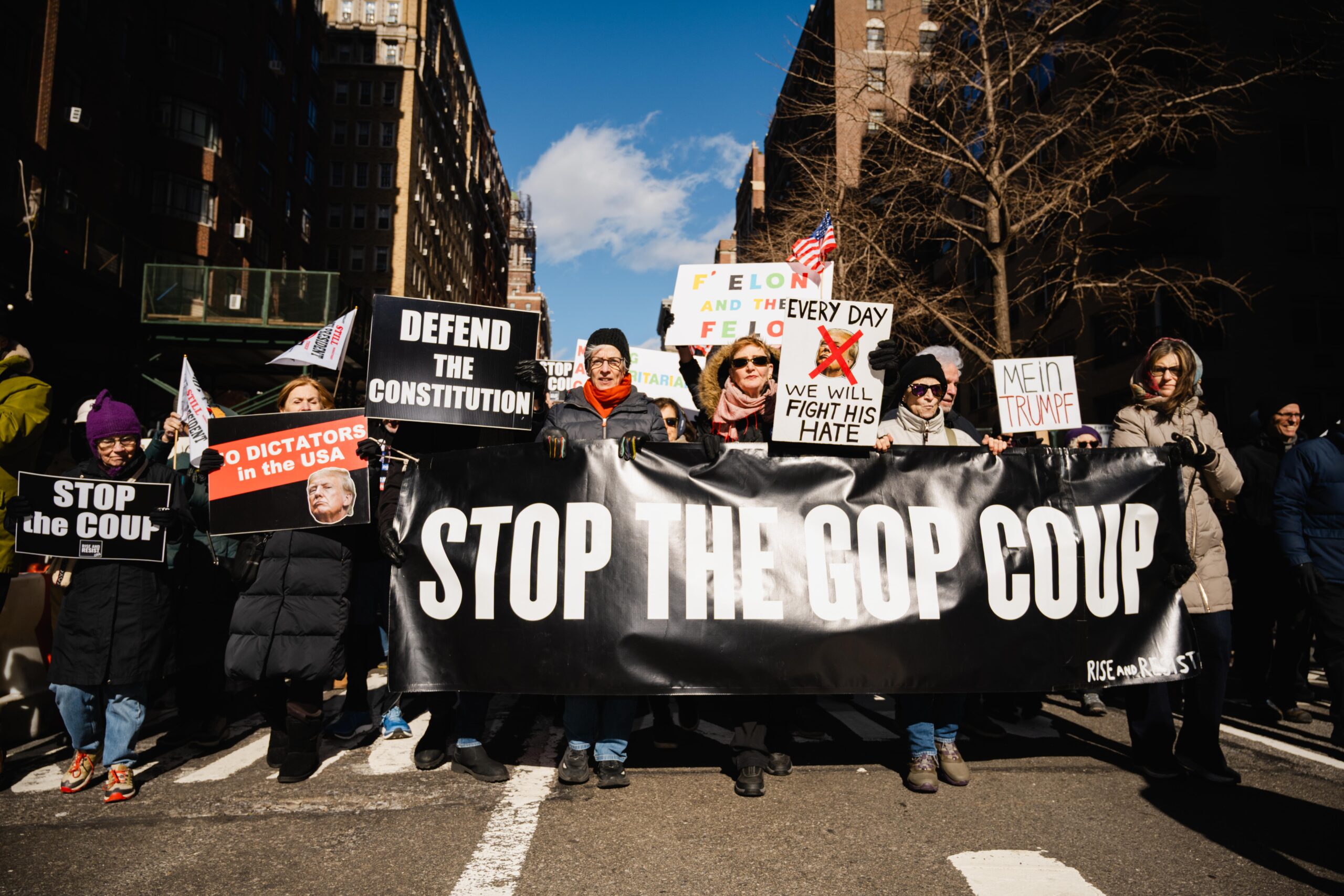 Protesters hold a large black sign that reads “Stop the coup”.