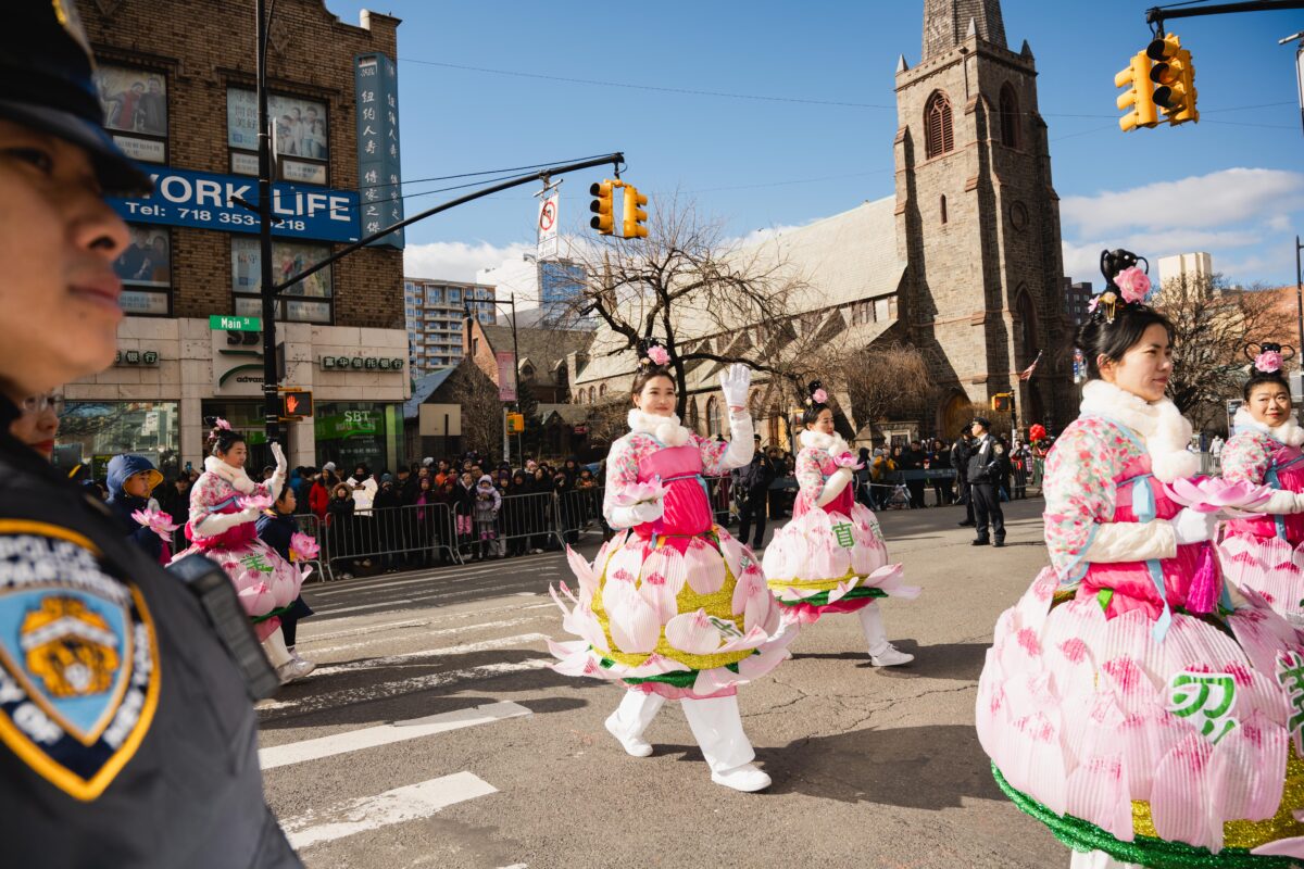 Parade participants in lotus costumes wave to spectators. 