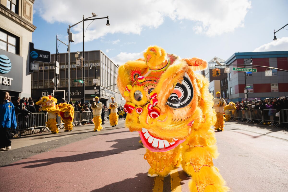 A yellow lion puppet in the middle of the street parade. 